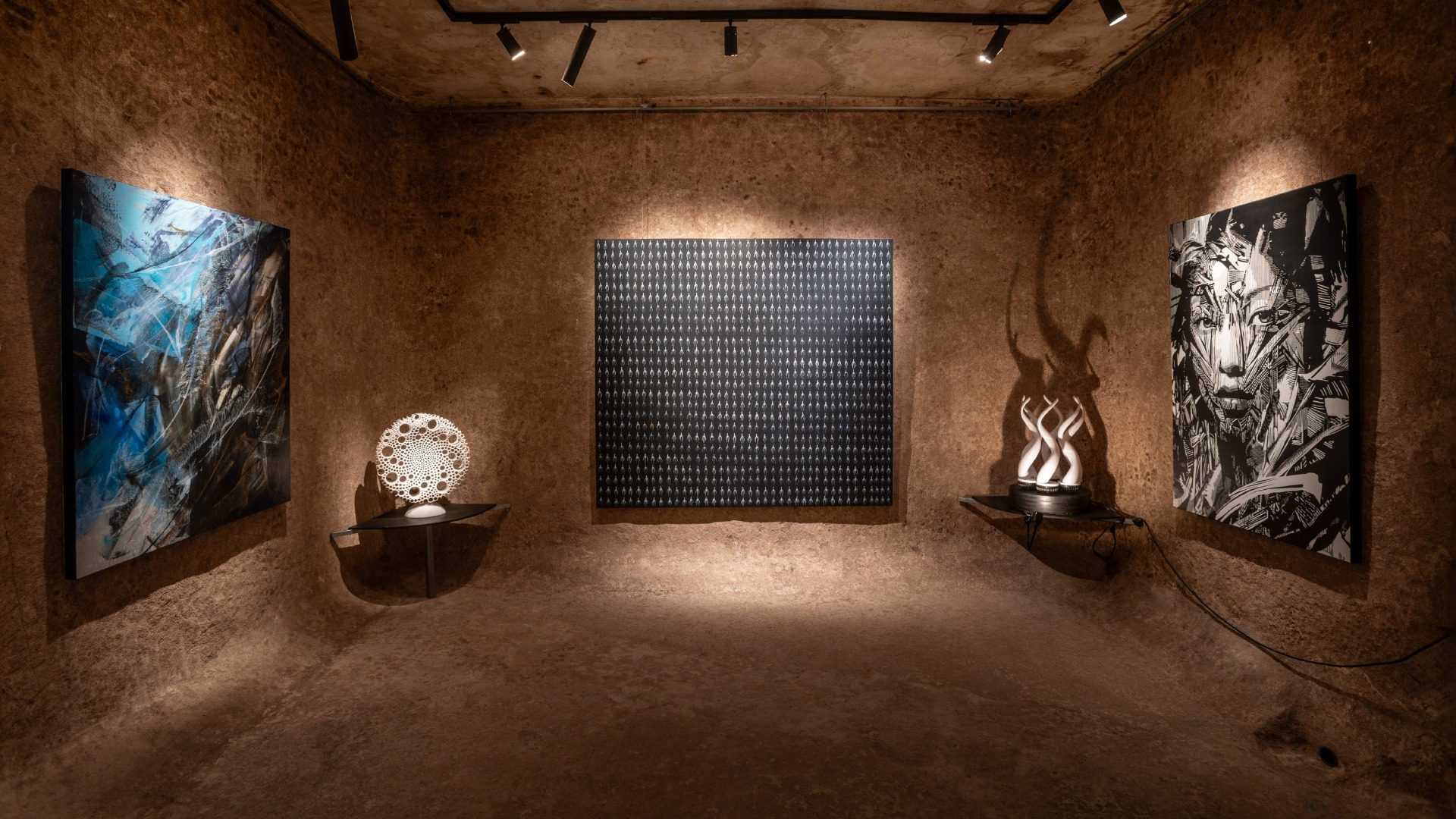 Unique underground art gallery interior featuring brutalist architecture at Because Art Matters Lisbon, with textured walls and illuminated paintings and sculptures.